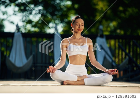 In the lotus pose. Young woman in yoga clothes is outdoors In the lotus pose. Young woman in yoga clothes is outdoors 128591602