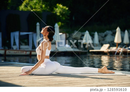 Doing yoga exercises. Woman near pool Doing yoga exercises. Woman near pool 128591610