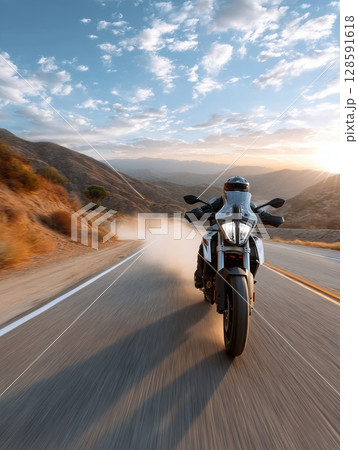 Motorcyclist riding on scenic mountain road at sunrise. Motorcyclist riding on scenic mountain road at sunrise. 128591618