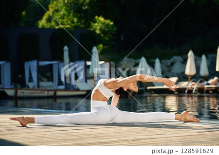 Flexible body. Woman near pool is doing yoga exercises Flexible body. Woman near pool is doing yoga exercises 128591629