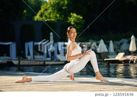 Doing professional exercises. Woman near pool is doing yoga 128591636
