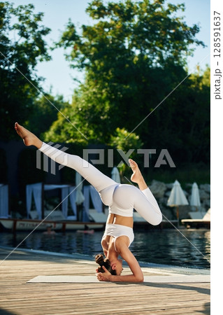 Doing professional exercises. Woman near pool is doing yoga 128591637