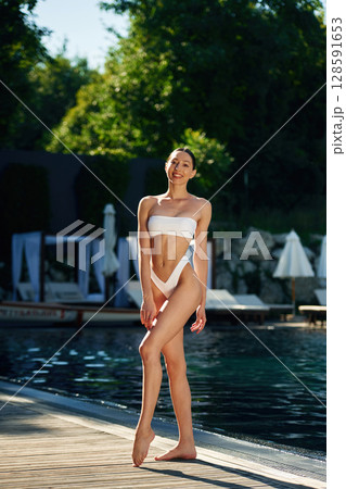 Full height photo. Woman in white underwear is near the pool 128591653