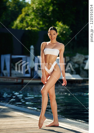 Full height photo. Woman in white underwear is near the pool Full height photo. Woman in white underwear is near the pool 128591654