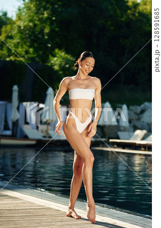 Young adult woman in white underwear is standing near the pool 128591685