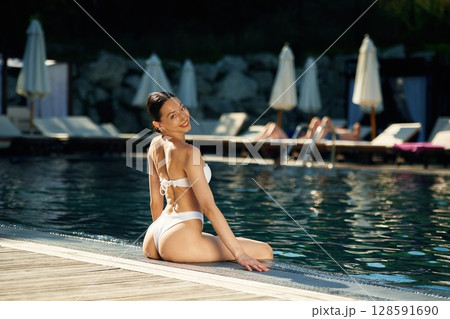 Sitting and relaxing. Woman in white underwear is in the pool Sitting and relaxing. Woman in white underwear is in the pool 128591690