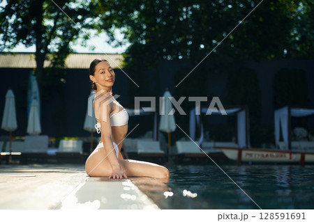 Sitting and relaxing. Woman in white underwear is in the pool 128591691