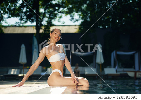 Sitting and relaxing. Woman in white underwear is in the pool 128591693