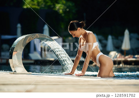Conception of resort and relax. Woman in white underwear is in the pool Conception of resort and relax. Woman in white underwear is in the pool 128591702