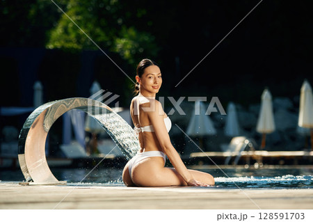Conception of resort and relax. Woman in white underwear is in the pool Conception of resort and relax. Woman in white underwear is in the pool 128591703