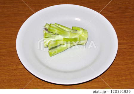 白い皿に乗せた生のブロッコリーの茎（木目背景） 128591929