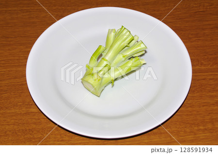 白い皿に乗せた生のブロッコリーの茎（木目背景） 128591934