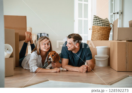 New owners are smiling. Young couple with dog are moving to new home New owners are smiling. Young couple with dog are moving to new home 128592273