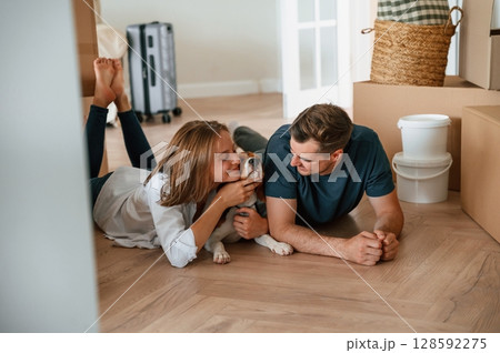 Happy young couple with dog are moving to new home. On the floor Happy young couple with dog are moving to new home. On the floor 128592275