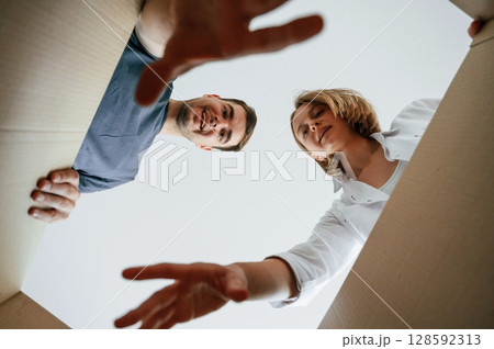 View from the inside of a box. Young couple moving to new home View from the inside of a box. Young couple moving to new home 128592313