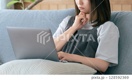 ソファに座ってパソコンを使う女性 128592369