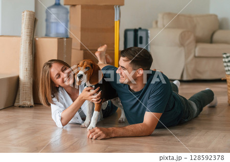 Lying down on the floor. Young couple with dog are moving to new home Lying down on the floor. Young couple with dog are moving to new home 128592378
