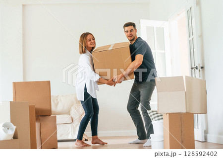 With one heavy box. Young couple moving to new home With one heavy box. Young couple moving to new home 128592402