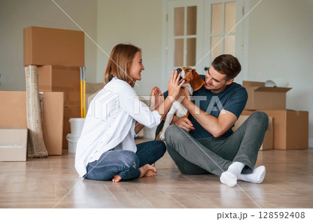 Playing with dog. Young couple is moving to new home Playing with dog. Young couple is moving to new home 128592408