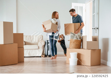 Two boxes in hands. Young couple with dog are moving to new home 128592425