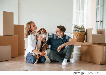 Sitting and playing with dog. Young couple are moving to new home 128592430
