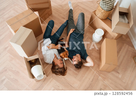 View from the top, lying down and resting. Young couple with dog are moving to new home View from the top, lying down and resting. Young couple with dog are moving to new home 128592456