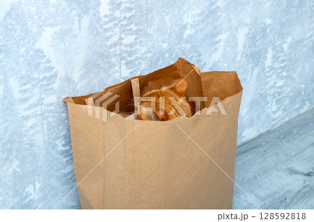 A brown paper bag filled with freshly baked bread sitting on a table 128592818