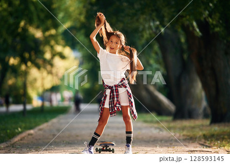 Playing with the hair, going crazy. Happy little girl with skateboard outdoors Playing with the hair, going crazy. Happy little girl with skateboard outdoors 128593145