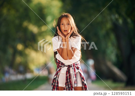 Shocked young girl in casual clothes is in the public park outdoors 128593151