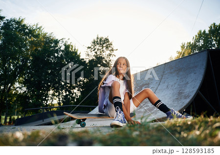 Beautiful summer time in the park, sitting. Happy little girl with skateboard outdoors 128593185