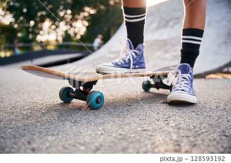 Standing on skateboard on one leg. Close up view of a young girl legs in blue shoes Standing on skateboard on one leg. Close up view of a young girl legs in blue shoes 128593192