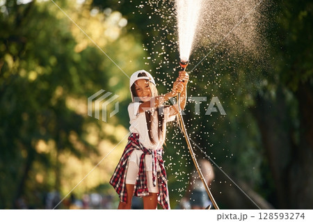 Flow of water, having fun. Young girl in casual clothes is in the public park outdoors Flow of water, having fun. Young girl in casual clothes is in the public park outdoors 128593274