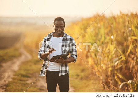 Holding digital tablet. Beautiful African American man is in the agricultural field Holding digital tablet. Beautiful African American man is in the agricultural field 128593425