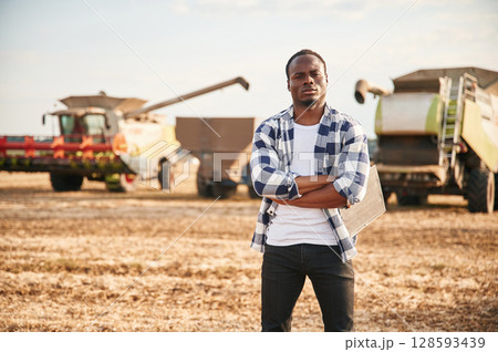 Standing with arms crossed. Beautiful African American man is in the agricultural field 128593439