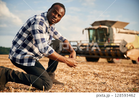 Machinery behind. Beautiful African American man is in the agricultural field 128593462