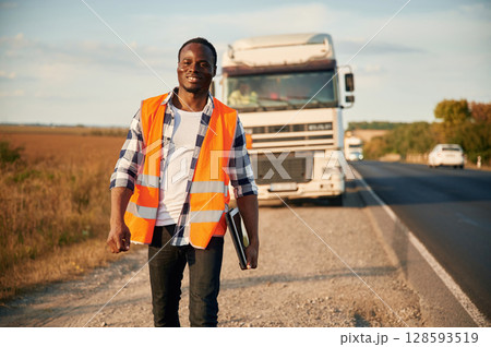 Front view. Black man is standing on the road with truck on it 128593519