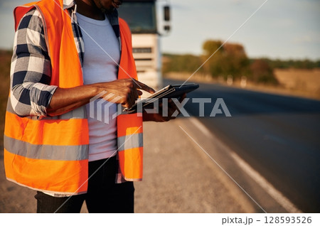 Modern technology concept. With tablet. Black man is standing on the road with truck on it 128593526
