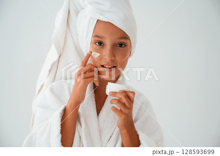 Putting cream on the face. Conception of beauty and self care. Young girl is in the studio Putting cream on the face. Conception of beauty and self care. Young girl is in the studio 128593699
