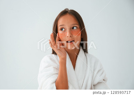 With eye patches on the face. Conception of beauty and self care. Young girl is in the studio 128593717