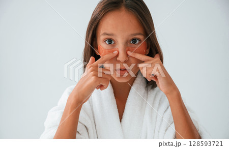 Orange colored eye patches on the face. Conception of beauty and self care. Young girl is in the studio Orange colored eye patches on the face. Conception of beauty and self care. Young girl is in the studio 128593721