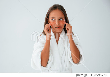 Young girl is in the studio using eye patches on the face Young girl is in the studio using eye patches on the face 128593730