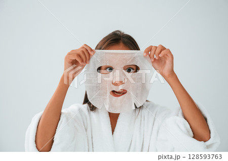 Playing and holding mask for the face. Conception of beauty and self care. Young girl is in the studio Playing and holding mask for the face. Conception of beauty and self care. Young girl is in the studio 128593763