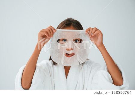 Playing and holding mask for the face. Conception of beauty and self care. Young girl is in the studio Playing and holding mask for the face. Conception of beauty and self care. Young girl is in the studio 128593764