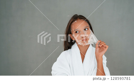 Funny facial expression. Playing with mask. Conception of beauty. Young girl is in the studio Funny facial expression. Playing with mask. Conception of beauty. Young girl is in the studio 128593781
