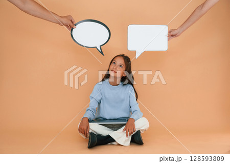 Thoughts stickers above. Sitting with laptop. Cute young girl is in the studio against background Thoughts stickers above. Sitting with laptop. Cute young girl is in the studio against background 128593809