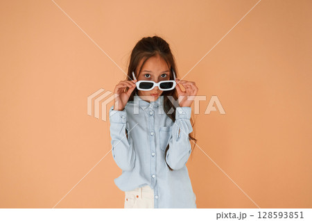 Funny facial expression and emotions. In sunglasses. Cute young girl is in the studio against background Funny facial expression and emotions. In sunglasses. Cute young girl is in the studio against background 128593851