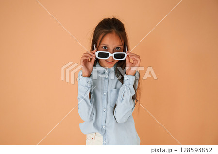 Funny facial expression and emotions. In sunglasses. Cute young girl is in the studio against background 128593852