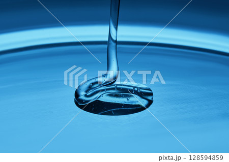 The texture of a cosmetic product in the form of jelly or gel on a blue background. The texture of a cosmetic product in the form of jelly or gel on a blue background. 128594859