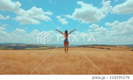 Woman in expansive golden field embracing the boundless sky and nature's beauty 128595276