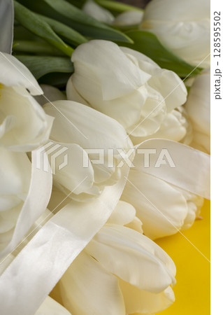 tulips on yellow paper and white ribbon , yellow paper and white tulip flowers with ribbon tulips on yellow paper and white ribbon , yellow paper and white tulip flowers with ribbon 128595502